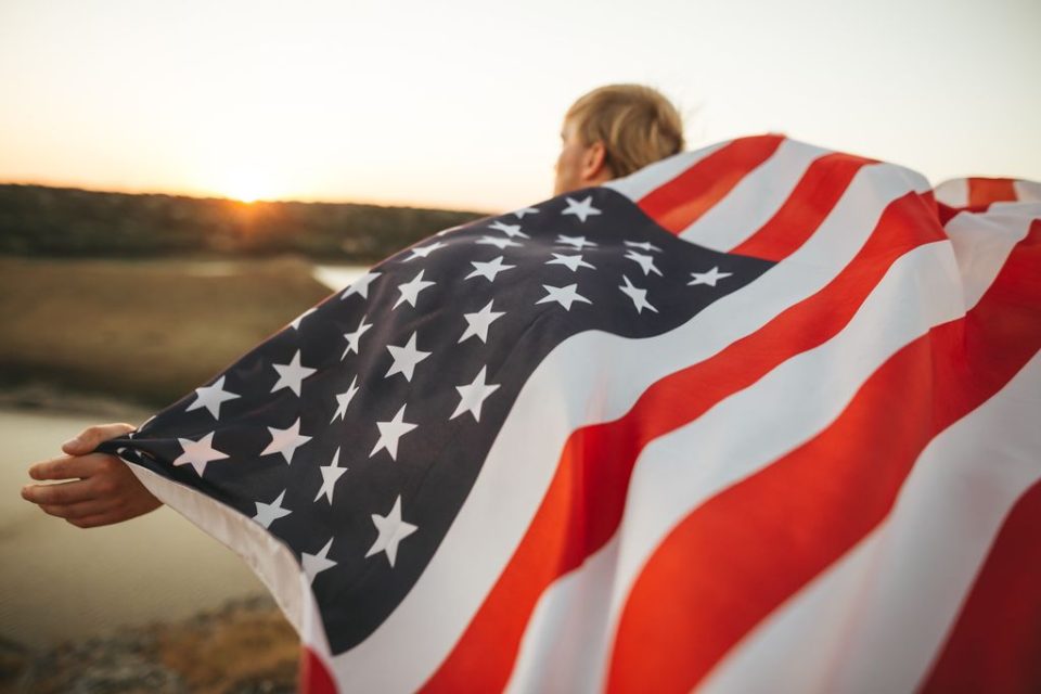 Young Man Holding An American Flag At Sunset